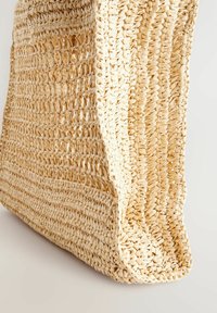 Vävd stråtkasse i naturlig beige, med en öppen struktur, mjuka kanter och en texturerad yta, designad för mångsidig användning.