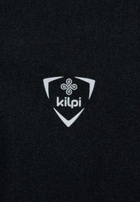 Tela negra con el logo blanco de "kilpi" dentro de una forma de escudo, con acentos triangulares distintivos y un fondo texturizado.