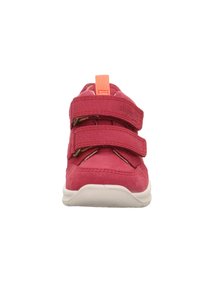 Rosa synthetische Schuhe mit zwei Klettverschlüssen und einer leuchtend orangefarbenen Zuglasche. Sie verfügen über eine weiße flexible Sohle und dezente Nähdetails.