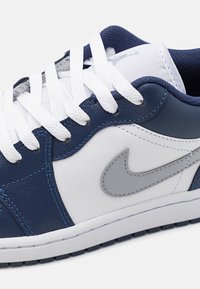 Gros plan d'une basket bleu marine et blanche avec des lacets blancs et un logo Nike swoosh gris sur le côté.