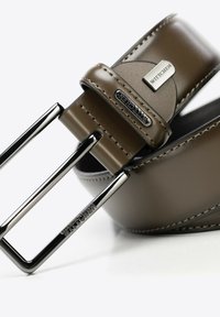Cintura in pelle marrone con una texture liscia, dotata di una fibbia rettangolare in argento e dettagli di cucitura sottili. Marchio visibile sulla pelle.