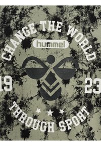 T-shirt graphique en vert olive avec texture marbrée noire. Présente un texte blanc : "CHANGEZ LE MONDE À TRAVERS LE SPORT" et un design de logo central.