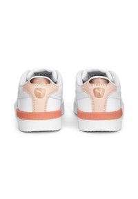 Valkoiset tennarit, joissa on persikkasävy kantapään ja logon kohdalla, nähtynä takaa, esittelee siistin ja modernin muotoilun.