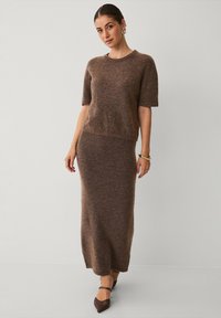 Brun strikket to-dels outfit bestående af en kortærmet top og en lang, tætsiddende nederdel. Blød tekstur med en let fuzzy overflade.
