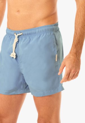 Siniset uima-shortit, jotka on valmistettu kevyestä kankaasta ja joissa on elastinen vyötärö, jossa on nyöri, sekä pieni etiketti sivussa.