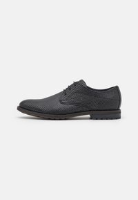 Chaussures habillées en cuir noir avec une surface texturée, un nez pointu et un design à lacets. Équipées d'une semelle en caoutchouc et d'une finition minimale.