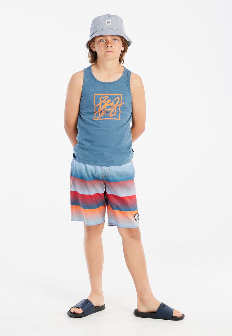 Blauwe tanktop met oranje opdruk, kleurrijke gestreepte zwemshorts in blauw, rood en wit, grijze bucket hat en zwarte slide sandalen.