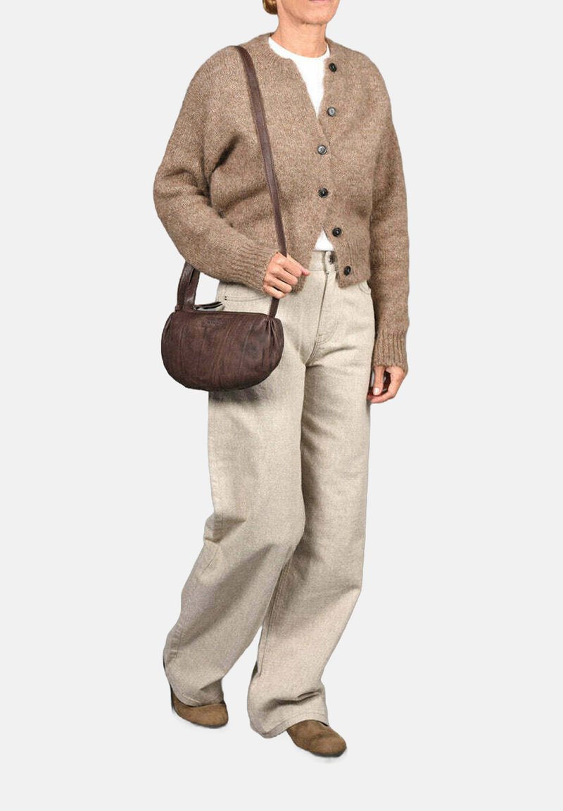 Cardigan de lana marrón con botones, combinado con pantalones de pierna ancha en un tono beige claro. Un pequeño bolso de cuero marrón completa el conjunto.
