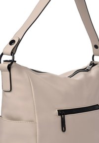 Bolso de mano de cuero beige con una correa de hombro desmontable, que cuenta con un cierre con cremallera y un bolsillo con cremallera negro en la parte delantera. Textura suave.