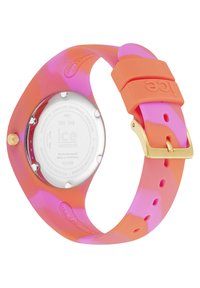 Montre en silicone colorée avec un bracelet dégradé rose et orange, des accessoires en or et un fond de boîte transparent affichant des informations sur la marque.