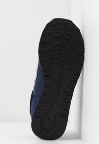 Blå atletisk skosula har en strukturerad svart gummiyta med ett mönster av däckspår. Varumärke synligt på mellansulan.