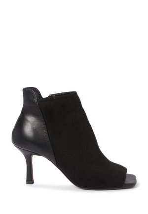 Bottine noire à talon, alliant daim et cuir, avec un design à bout ouvert, une silhouette épurée et un talon haut. Fermeture éclair à l'arrière.