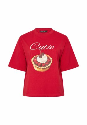 Camiseta roja de manga corta con texto "Cutie" y un gráfico de tarta de cereza cubierta con crema batida en el frente.
