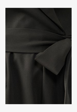 Black fabric garment with a smooth texture, featuring a tied sash at the waist and pleated details along the bottom.