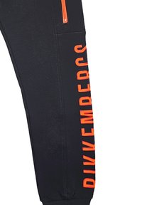 Pantaloni jogger neri con una tasca con zip arancione, caratterizzati da un audace testo verticale "DIVEEMBERS" lungo il lato in un font moderno. Tessuto morbido e texturizzato.