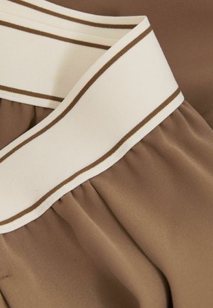 Bruine stof met een gladde textuur, uitgerust met een brede crèmekleurige tailleband met bruine strepen, en daaronder geplooide details voor extra flair.