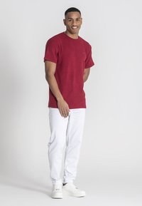 Röd ribbad t-shirt med korta ärmar, kombinerad med vita jeans och vita sneakers. Enkel design, mjuk textur och inga synliga mönster.