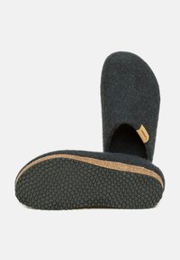 Chaussons en feutre noir à enfiler avec une semelle en liège et un profil en caoutchouc, dotés d'un orteil arrondi et d'une petite étiquette de marque sur le côté.