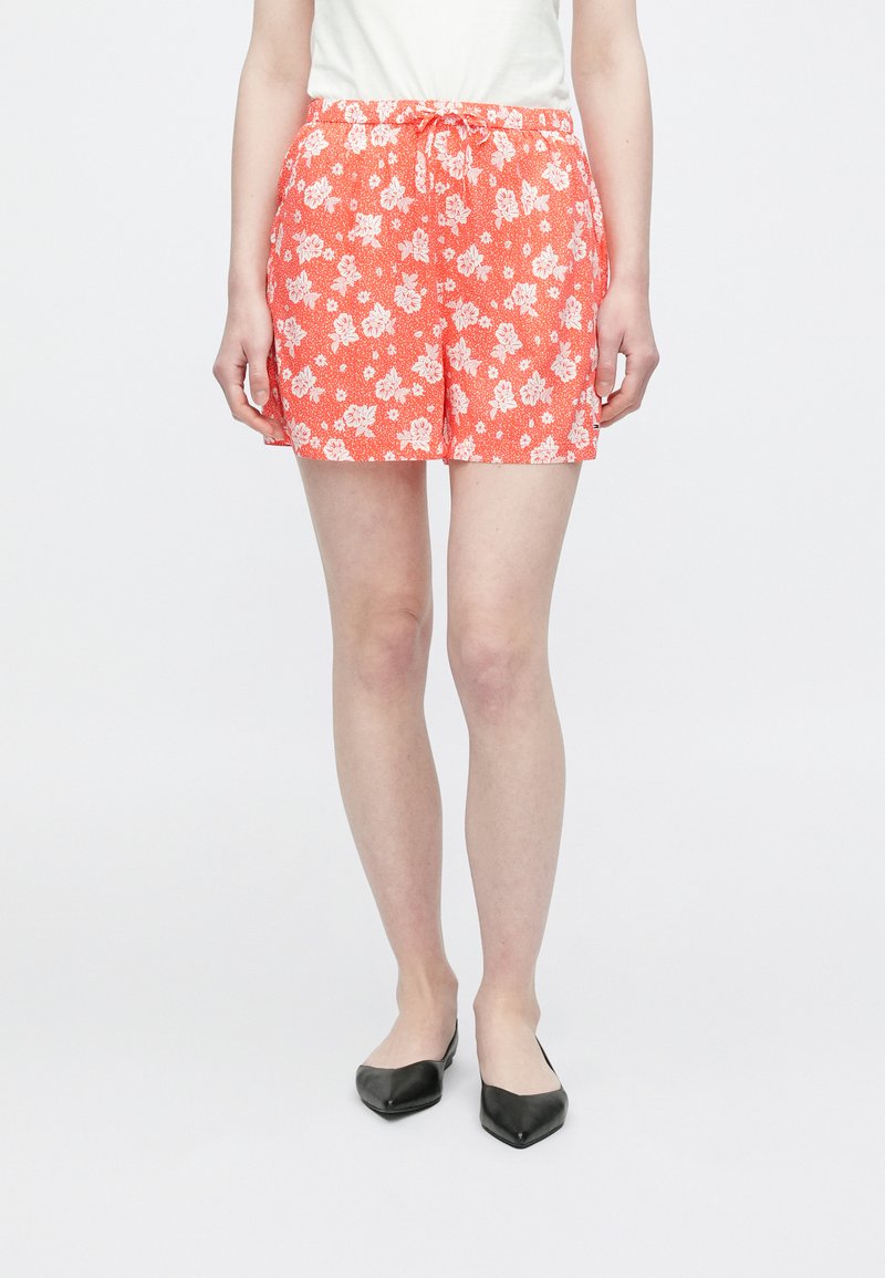 Röda shorts med blommönster och vita blommor, elastisk midja och dragsko. Tillverkade av lätt tyg med lös passform.