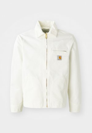 Fehér pamut dzseki, galléros nyakkal, arany cipzárral és logóval ellátott mellzsebbe. Oldalzsebekkel és laza szabással rendelkezik.