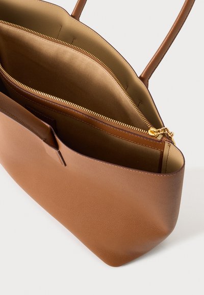 Sac cabas en cuir marron avec deux poignées, ouverture supérieure dévoilant un intérieur beige et un compartiment intérieur zippé avec une tirette dorée.