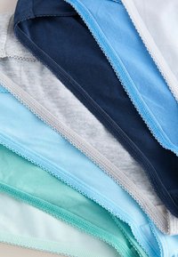 Sous-vêtements en coton empilés pour femmes dans différentes nuances de bleu, sarcelle, gris et blanc, avec une bordure en dentelle festonnée sur les bords.