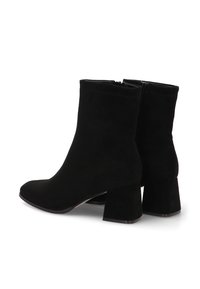 Botas de ante negro hasta el tobillo con puntera cuadrada, tacón ancho y cremallera lateral. La parte superior tiene una textura suave y lisa sin patrones visibles.