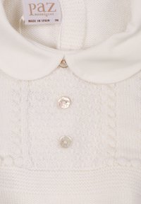 Maglione bianco a maglia con motivo texturizzato, colletto bianco rotondo e tre bottoni perline sul davanti. Prodotto in Spagna.