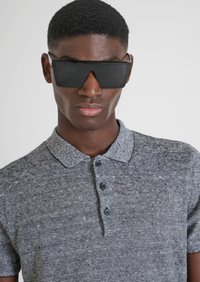 Occhiali da sole neri di grandi dimensioni e una polo grigia a righe con colletto e tre bottoni, che mette in mostra un tessuto texture.