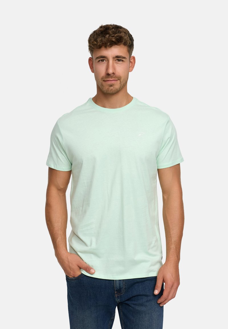 Light green cotton t-shirt with a round neckline and short sleeves, featuring a small logo on the chest and a relaxed fit. Worn with dark jeans.