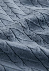 Gray knitted fabric featuring a raised cable pattern with diagonal lines and soft texture, suitable for sweaters or blankets.