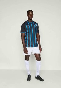 Camisa de futebol listada em preto e azul, com mangas curtas, combinada com calções e meias brancas. Botas pretas completam o visual atlético.