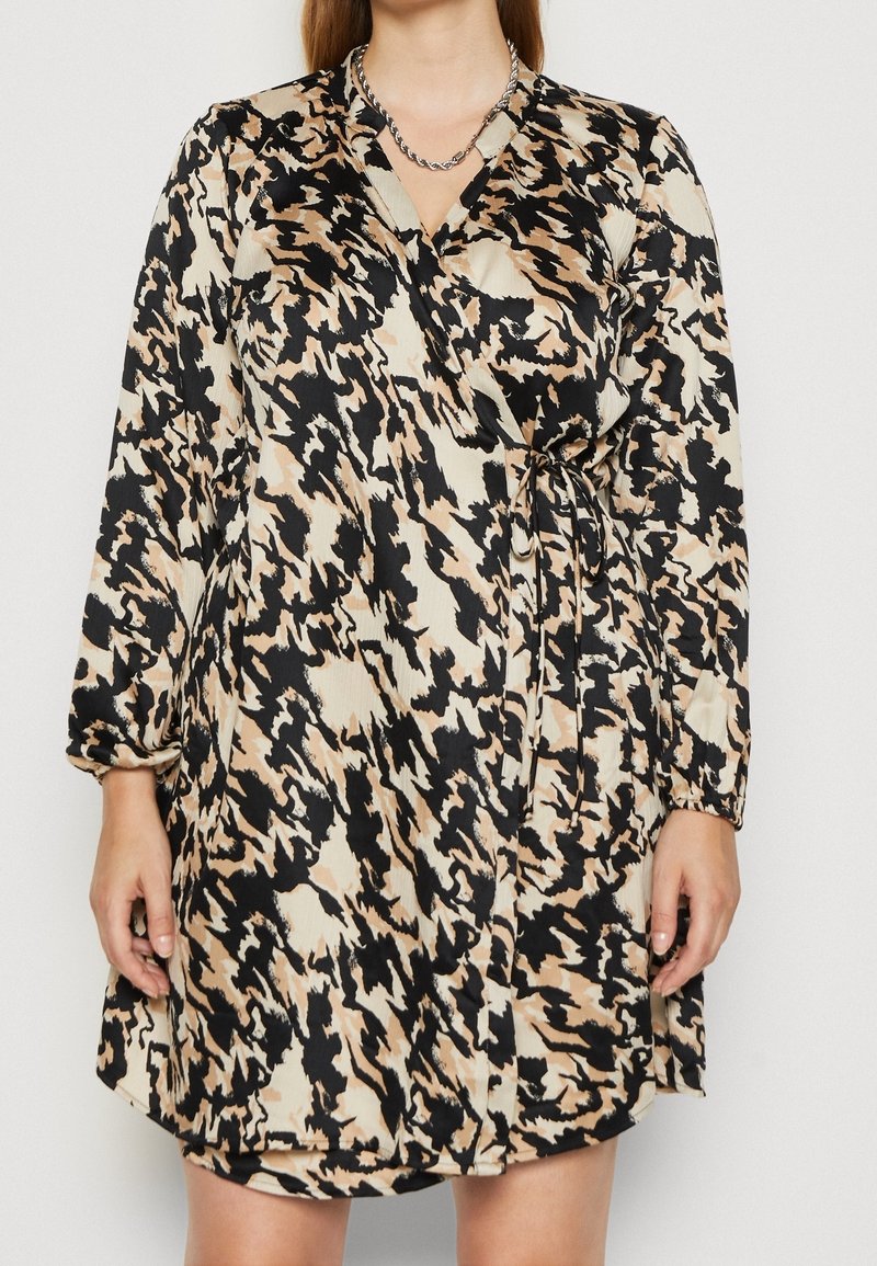 Robe enveloppante à motifs noirs et beiges avec de longues manches, une ceinture à la taille et un décolleté en V profond. Tissu lisse et fluide avec une finition brillante.