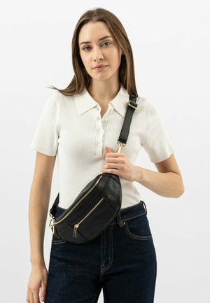 Marsupio in pelle nera con due tasche con zip, dettagli in metallo dorato e tracolla regolabile, abbinato a una polo bianca a righe.
