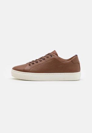 Niedrig geschnittene braune Leder-Sneaker mit strukturierten Oberflächen, Schnürverschluss, weißer Gummisohle und dezentem Seitenbranding auf einem schlichten weißen Hintergrund.