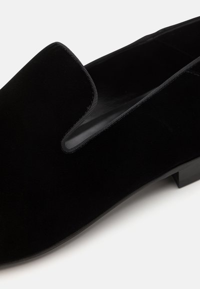 Černé sametové boty na slip-on s kulatou špičkou, hladkou texturou a minimalistickým designem. Ozdobené jemným prošíváním kolem otvoru.