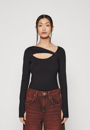 Black long-sleeve bodysuit with asymmetric cutout at the neckline, featuring a smooth texture and fitted design. Paired with rust-colored jeans.