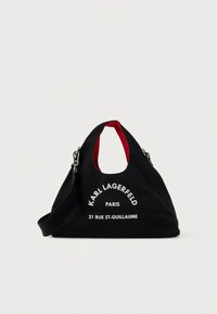 Black tote bag with red interior, silver hardware, and white "Karl Lagerfeld Paris 21 Rue St-Guillaume" text on front.