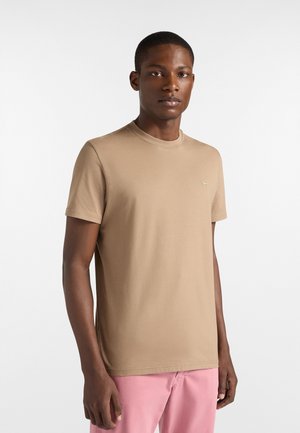 Beige T-Shirt mit kurzen Ärmeln aus weichem Baumwollmaterial, mit rundem Ausschnitt und kleinem Logodetail auf der linken Brust.