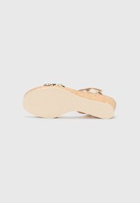 Sandale en liège à talon compensé avec une semelle texturée beige, dotée d'une sangle métallique et d'accents imprimé animal sur le rembourrage.