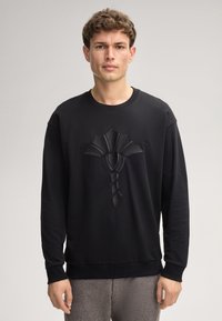 Felpa nera a maniche lunghe, con un design testurizzato e in rilievo sulla parte anteriore. Collo e polsini a costine e un fit rilassato.