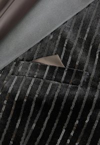 Black velvet fabric with vertical metallic sequins. Includes a gray satin pocket square in a tailored pocket. Smooth, textured finish.