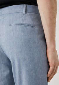  Lichtblauwe stoffen broek met een gestructureerde afwerking, voorzien van een achterzak en een getailleerd ontwerp, gladde randen en een aansluitende taille.