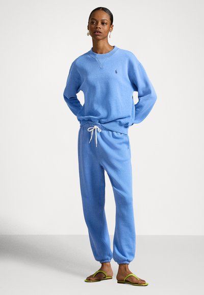 Lyseblå genser med ribbede mansjetter og nederkant, kombinert med matchende joggebukser med justerbar snor i midjen og elastiske ankler.