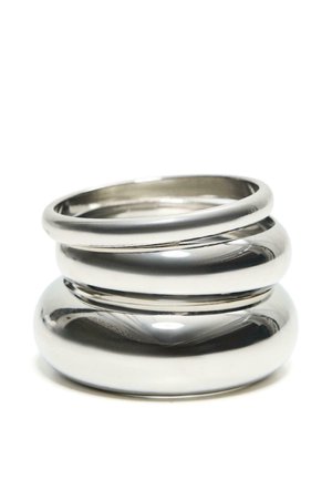 Trei inele metalice argintii lucioase stivuite, cu suprafețe netede și rotunjite pe un fundal alb.