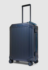 Hartschalenkoffer in Marineblau mit vertikalen Rippen, ausziehbarem Griff und vier Rollen. Verfügt über einen blauen Akzent und ein Zahlenschloss.