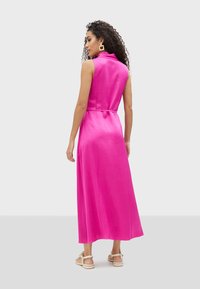 Vestido sin mangas fucsia con cuello alto, de largo maxi fluido y cintura ceñida, confeccionado en suave tela de satén.