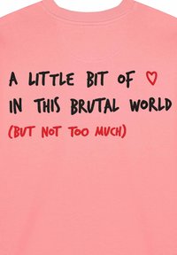 Ružičasti pamučni dukserica s crnim i crvenim tekstom: "MALO ❤️ U OVOM BRUTALNOM SVIJETU (ALI NE PREVIŠE)" na leđima.