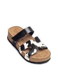 Black and white cow-print slide sandal with two wide straps, cork footbed, and textured sole for grip. Smooth leather accents.