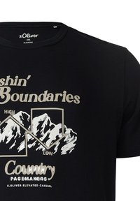 Zwarte T-shirt met een grafisch ontwerp van bergen en tekst in beige: "Pushin' Boundaries," "High," en "Low," met het logo van "Country Pacemakers" eronder.